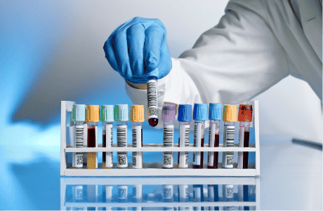 A photo of a scientist picking up a test tube vial full of blood out of a test tube rack