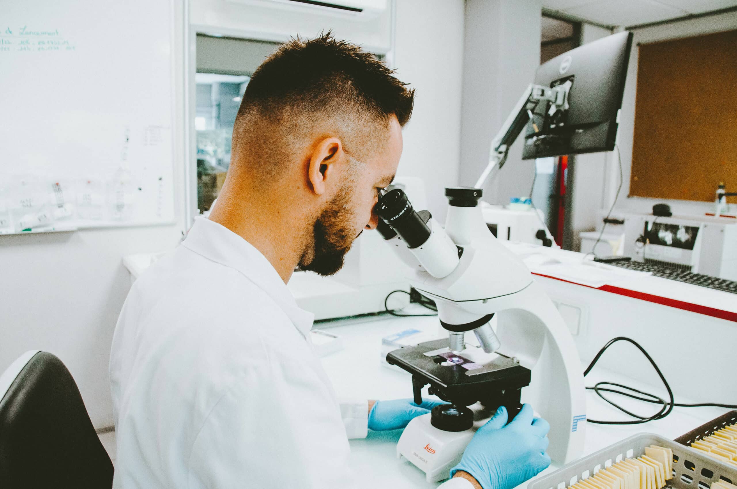 A scientist sat down in a lab using a microscope.